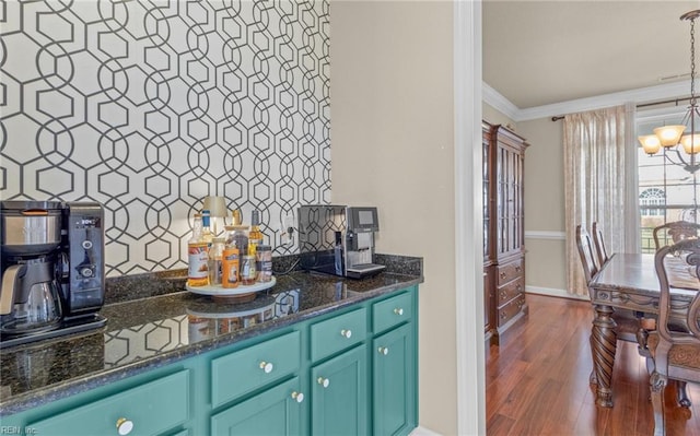 bar featuring dark wood-type flooring, a notable chandelier, dark stone countertops, crown molding, and pendant lighting