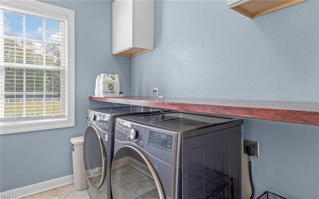 laundry room with light tile patterned flooring, plenty of natural light, cabinets, and washing machine and clothes dryer