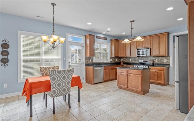 kitchen with tasteful backsplash, stainless steel appliances, sink, pendant lighting, and a center island