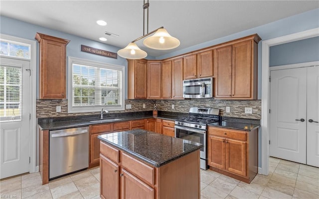 kitchen featuring pendant lighting, a wealth of natural light, a kitchen island, and appliances with stainless steel finishes