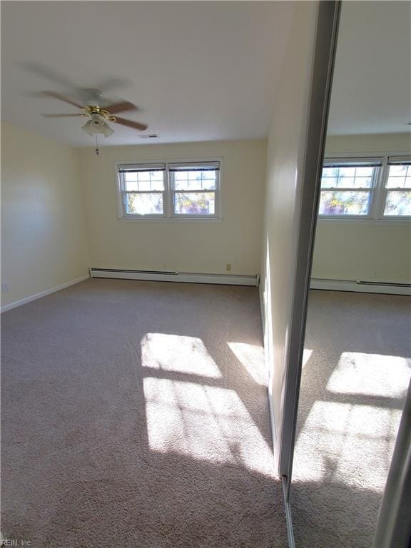 carpeted spare room featuring ceiling fan, a healthy amount of sunlight, and a baseboard radiator