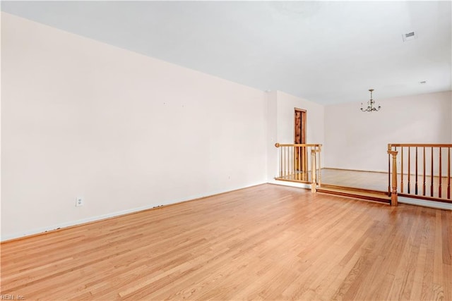 empty room with a chandelier and light wood-type flooring