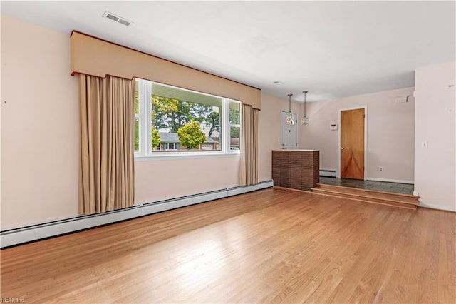 unfurnished room featuring light wood-type flooring and a baseboard heating unit