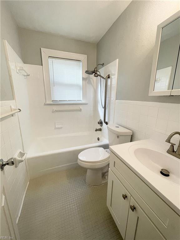 full bathroom with shower / bathing tub combination, vanity, tile patterned floors, toilet, and tile walls