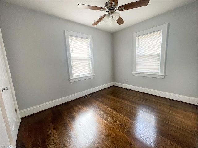 spare room with a wealth of natural light, ceiling fan, and dark hardwood / wood-style floors