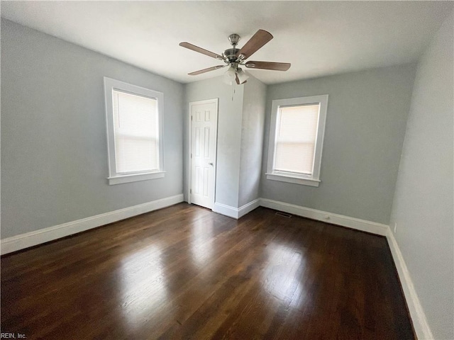 unfurnished bedroom with a closet, multiple windows, dark wood-type flooring, and ceiling fan