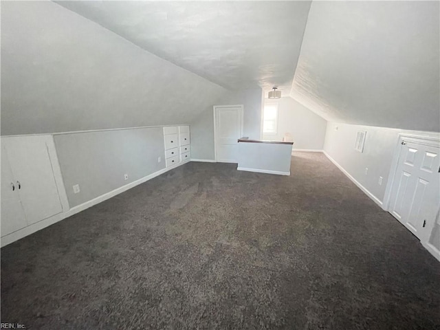 additional living space with dark carpet and vaulted ceiling