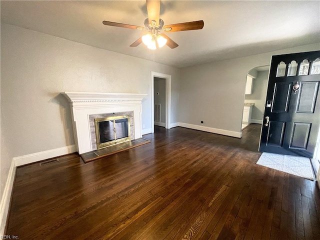 unfurnished living room with a tiled fireplace, ceiling fan, and dark hardwood / wood-style floors