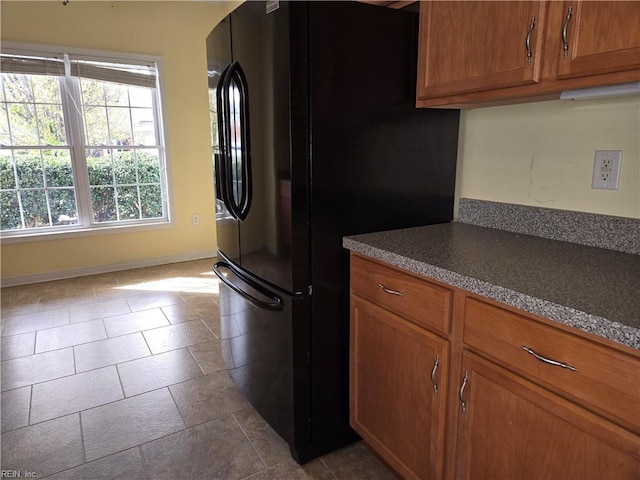 kitchen with black refrigerator and light tile patterned flooring