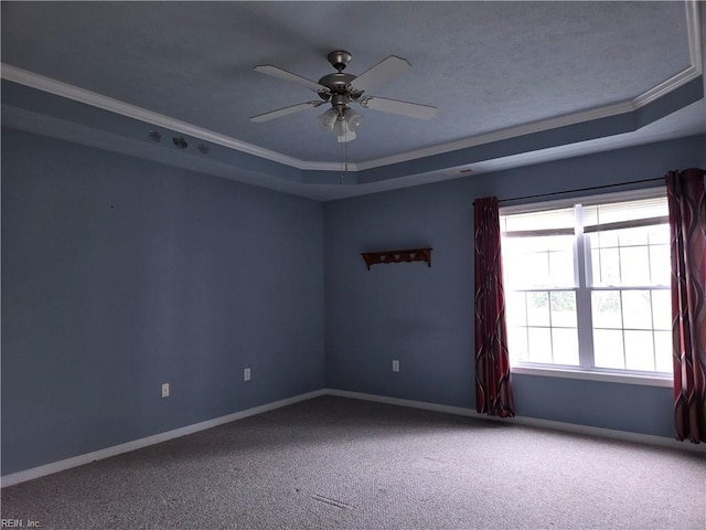 carpeted spare room with a tray ceiling, crown molding, and ceiling fan