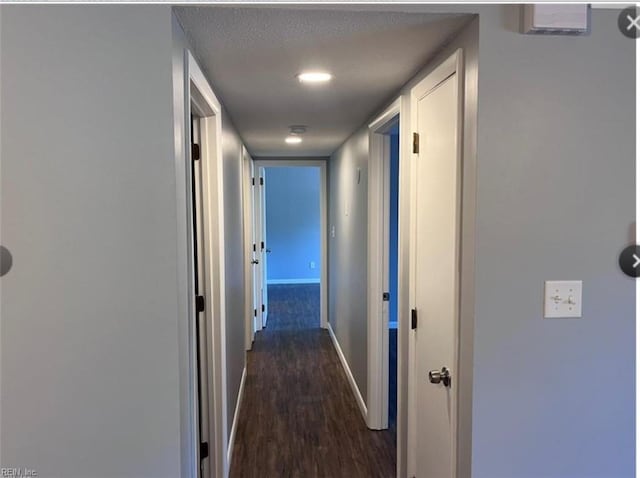 corridor with dark hardwood / wood-style floors and a textured ceiling