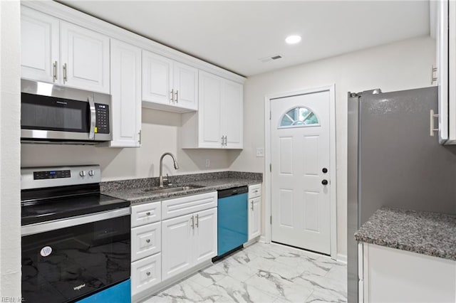 kitchen with white cabinets, stainless steel appliances, dark stone countertops, and sink