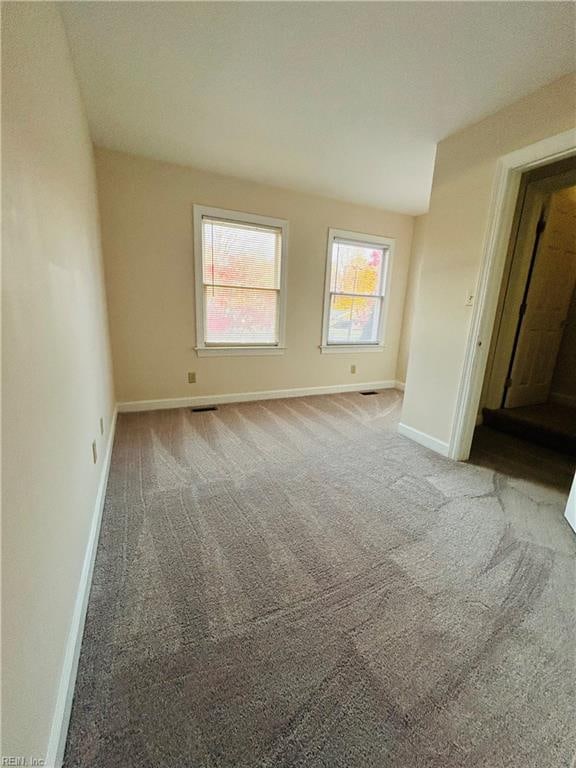 unfurnished bedroom with light carpet, visible vents, and baseboards