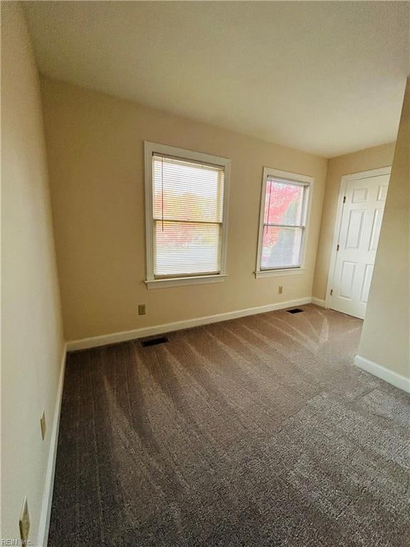 carpeted empty room featuring visible vents and baseboards