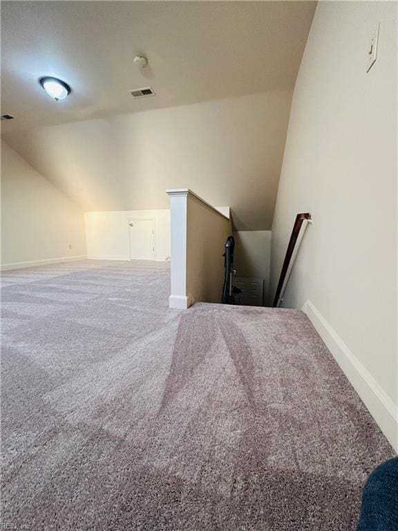 interior space featuring carpet, visible vents, vaulted ceiling, and baseboards