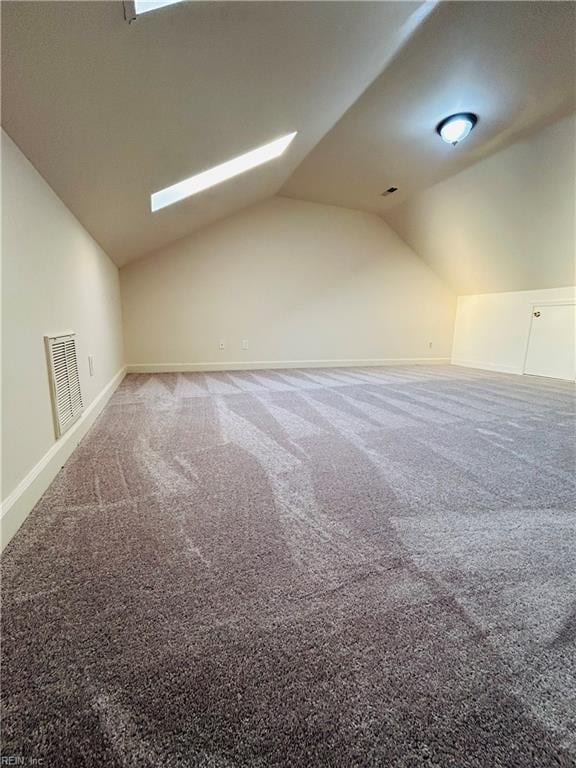 additional living space featuring vaulted ceiling with skylight, visible vents, and carpet flooring