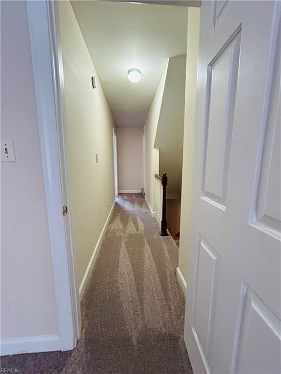 hallway with an upstairs landing, baseboards, and light colored carpet