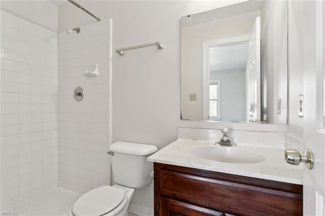 full bathroom featuring tiled shower, vanity, and toilet