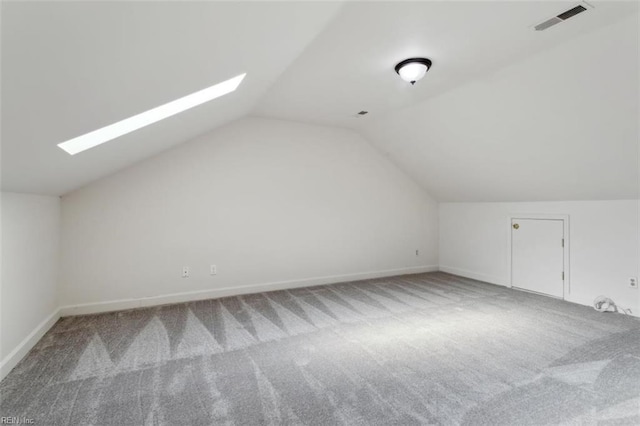 additional living space featuring vaulted ceiling with skylight, carpet flooring, visible vents, and baseboards