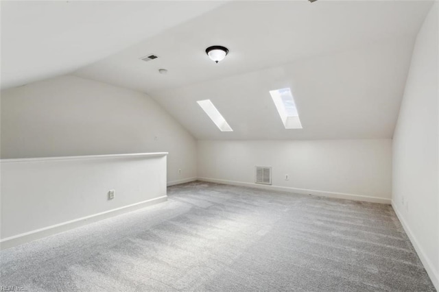 additional living space with vaulted ceiling with skylight, visible vents, and baseboards