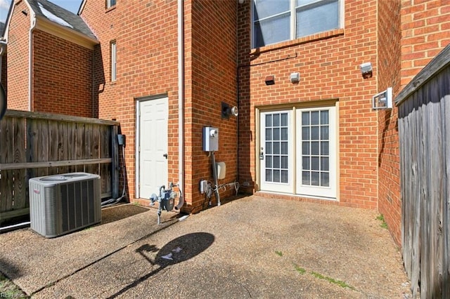 back of house with central air condition unit, a patio area, fence, and brick siding