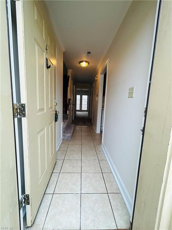 hall featuring visible vents, baseboards, and light tile patterned floors