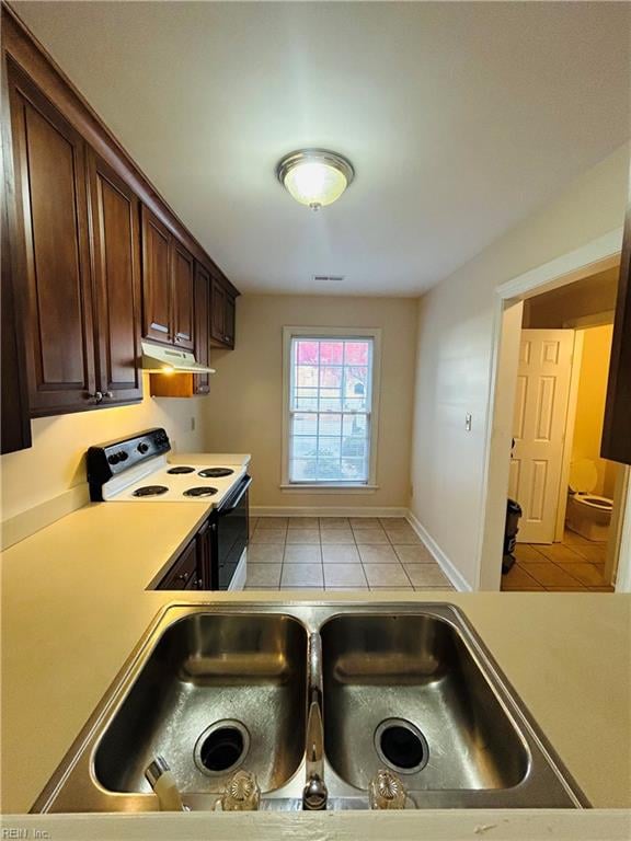 kitchen with electric range, light countertops, dark brown cabinets, under cabinet range hood, and a sink