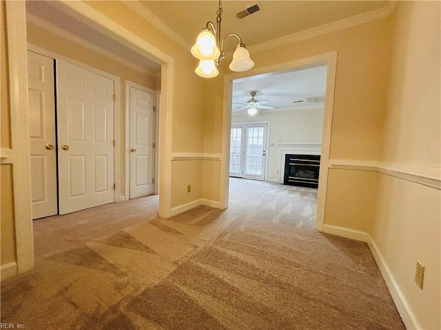 unfurnished dining area with carpet, visible vents, ornamental molding, a glass covered fireplace, and baseboards