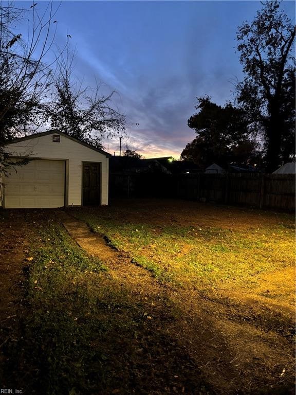 yard at dusk with a garage and an outbuilding