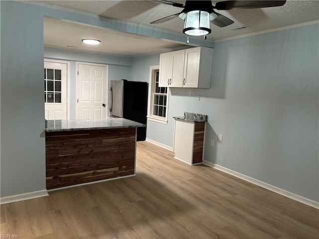 kitchen with stainless steel refrigerator, light stone countertops, crown molding, light hardwood / wood-style floors, and white cabinets