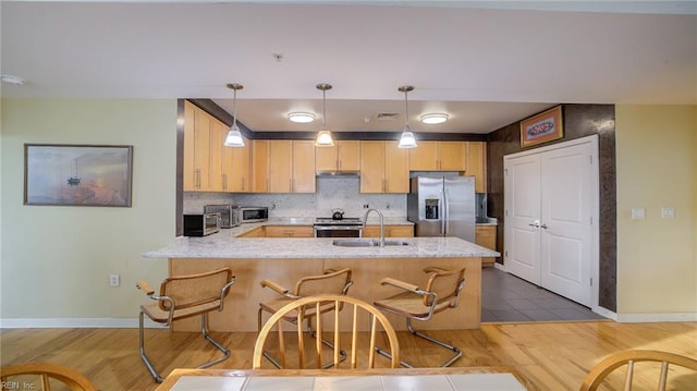 kitchen featuring hardwood / wood-style flooring, pendant lighting, sink, and stainless steel appliances