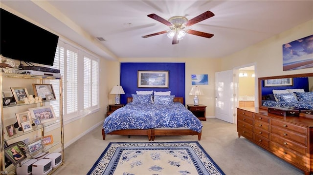 carpeted bedroom with ceiling fan, ensuite bathroom, and multiple windows