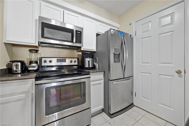 kitchen with dark stone countertops, white cabinetry, and appliances with stainless steel finishes