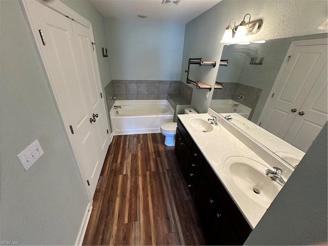 bathroom with a bathing tub, vanity, toilet, and wood-type flooring