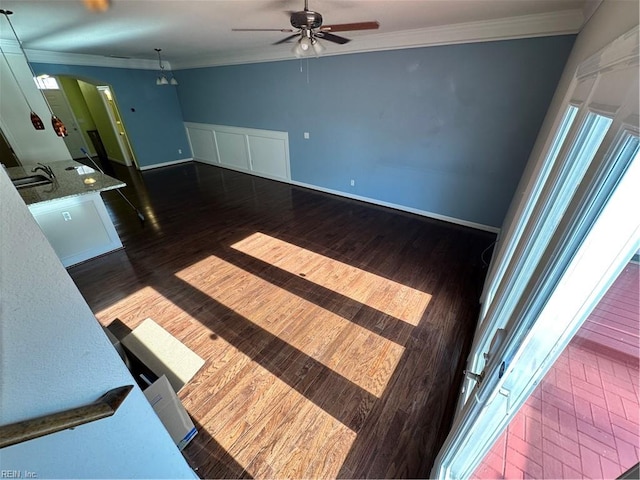 unfurnished living room with dark hardwood / wood-style floors, ornamental molding, and ceiling fan with notable chandelier