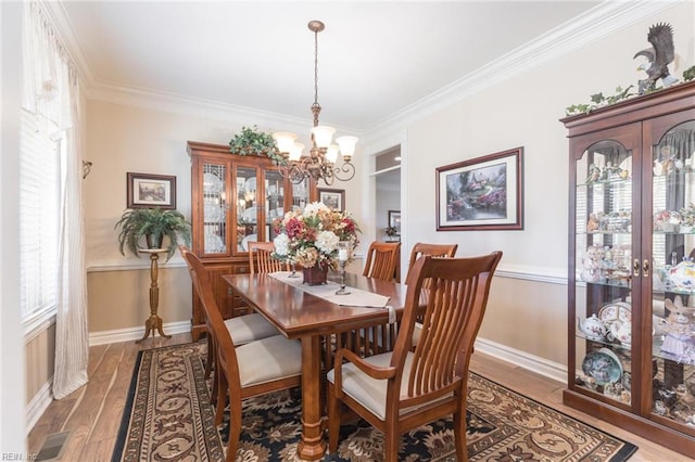 dining space featuring an inviting chandelier, crown molding, and hardwood / wood-style floors