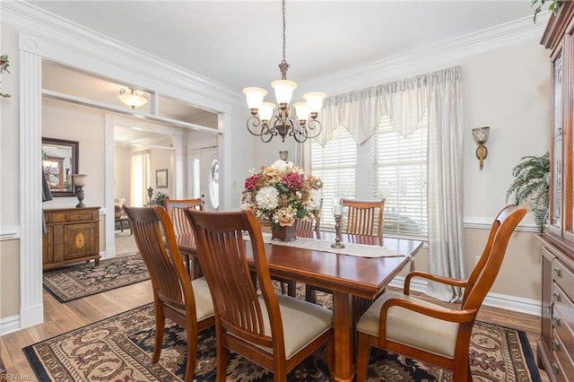 dining area featuring a chandelier, ornamental molding, and light hardwood / wood-style flooring