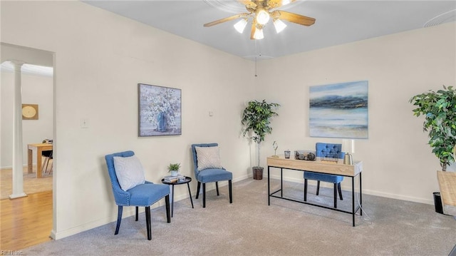 carpeted home office with decorative columns and ceiling fan