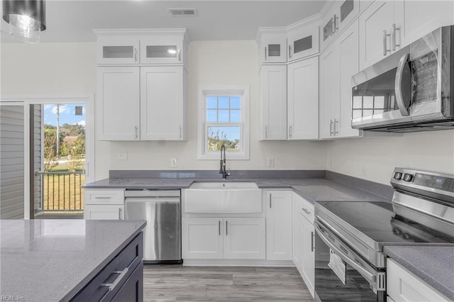 kitchen featuring white cabinets, sink, light hardwood / wood-style flooring, dark stone countertops, and appliances with stainless steel finishes