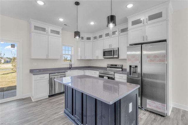 kitchen featuring hanging light fixtures, stainless steel appliances, white cabinetry, and a wealth of natural light