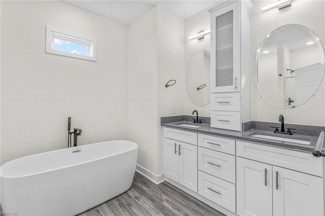 bathroom with a bathing tub, vanity, and wood-type flooring