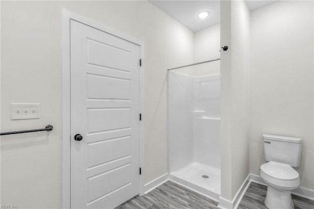 bathroom featuring a shower, wood-type flooring, and toilet