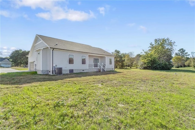 rear view of property with a garage, central air condition unit, and a yard