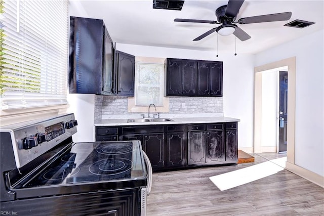 kitchen featuring light hardwood / wood-style floors, tasteful backsplash, sink, and black electric range