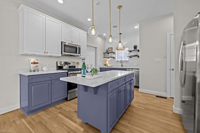 kitchen featuring light hardwood / wood-style flooring, white cabinets, decorative light fixtures, and appliances with stainless steel finishes