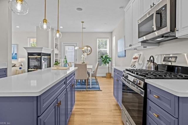 kitchen featuring a center island, blue cabinets, light hardwood / wood-style flooring, white cabinetry, and stainless steel appliances