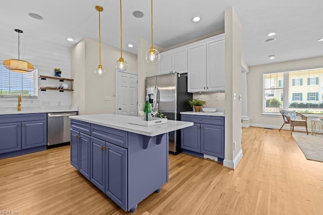 kitchen featuring pendant lighting, a kitchen island, blue cabinets, and appliances with stainless steel finishes