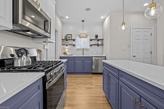 kitchen with blue cabinets, sink, decorative light fixtures, light hardwood / wood-style floors, and stainless steel appliances