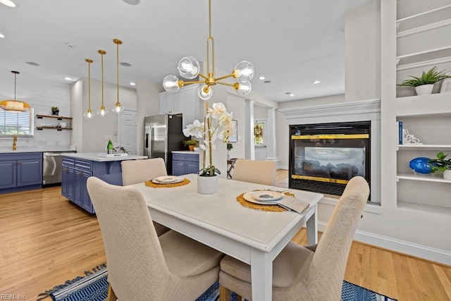 dining room with a notable chandelier, light wood-type flooring, and built in shelves