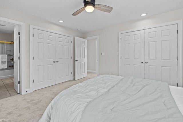 carpeted bedroom featuring ceiling fan and multiple closets